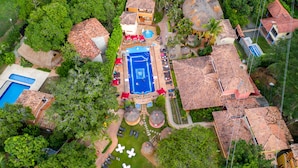An aerial view of a resort with a swimming pool, thatched-roof structures, and lush greenery. - Hosteria Tonusco Campestre (Santa Fe de Antioquia)