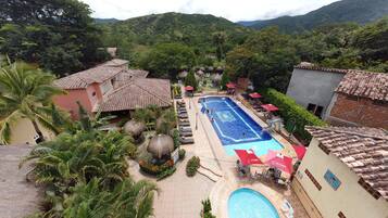 Un resort con piscina, sillas de descanso y vistas de las colinas circundantes.