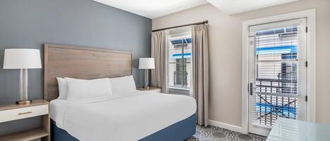 Habitación de hotel con cama, mesitas de noche, lámparas, ventana con cortinas y vistas al exterior.
