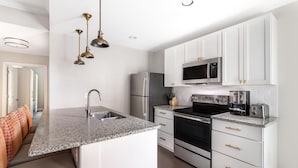 A modern kitchen with white cabinets, stainless steel appliances, and a granite countertop. - Hilton Vacation Club King 583 Charleston (Charleston)