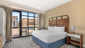 A hotel room with a large bed, a nightstand, a desk, and a view of the outside. - Hilton Vacation Club King 583 Charleston (Charleston)