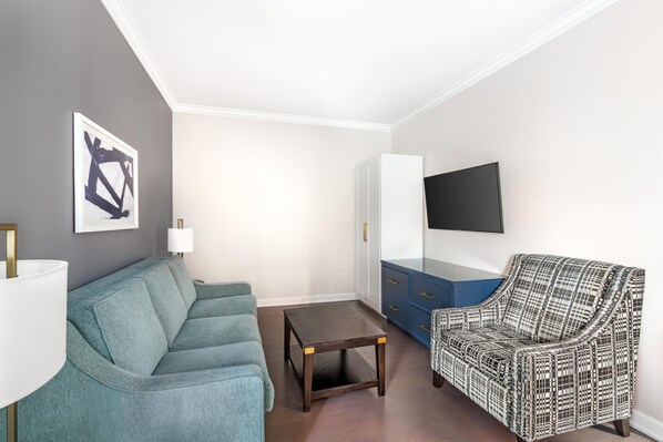 A living room with a sofa, a patterned armchair, a coffee table, a lamp, a TV, and a cabinet. - Hilton Vacation Club King 583 Charleston (Charleston)