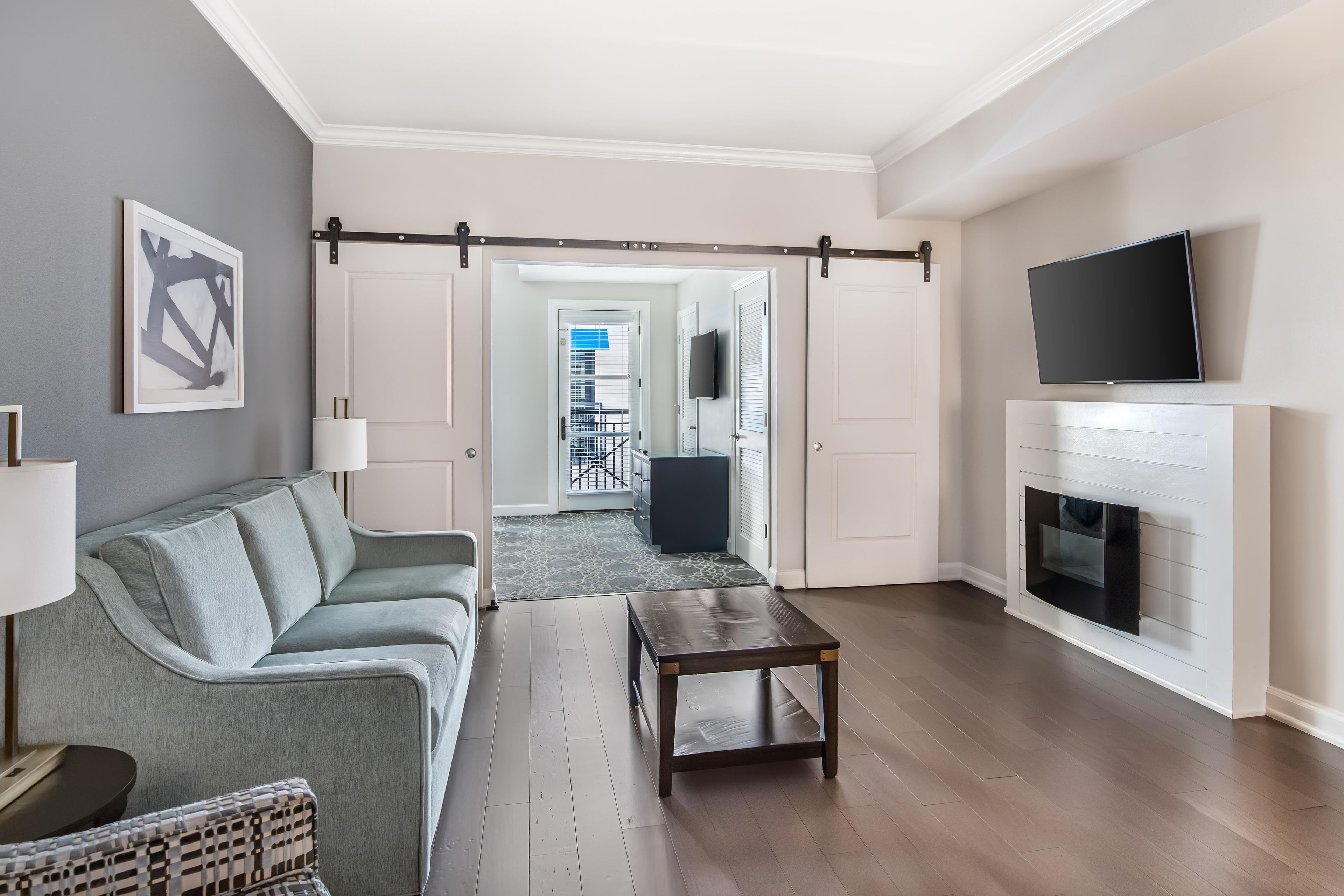 A modern living room with a sofa, a coffee table, a fireplace, and a television mounted on the wall.