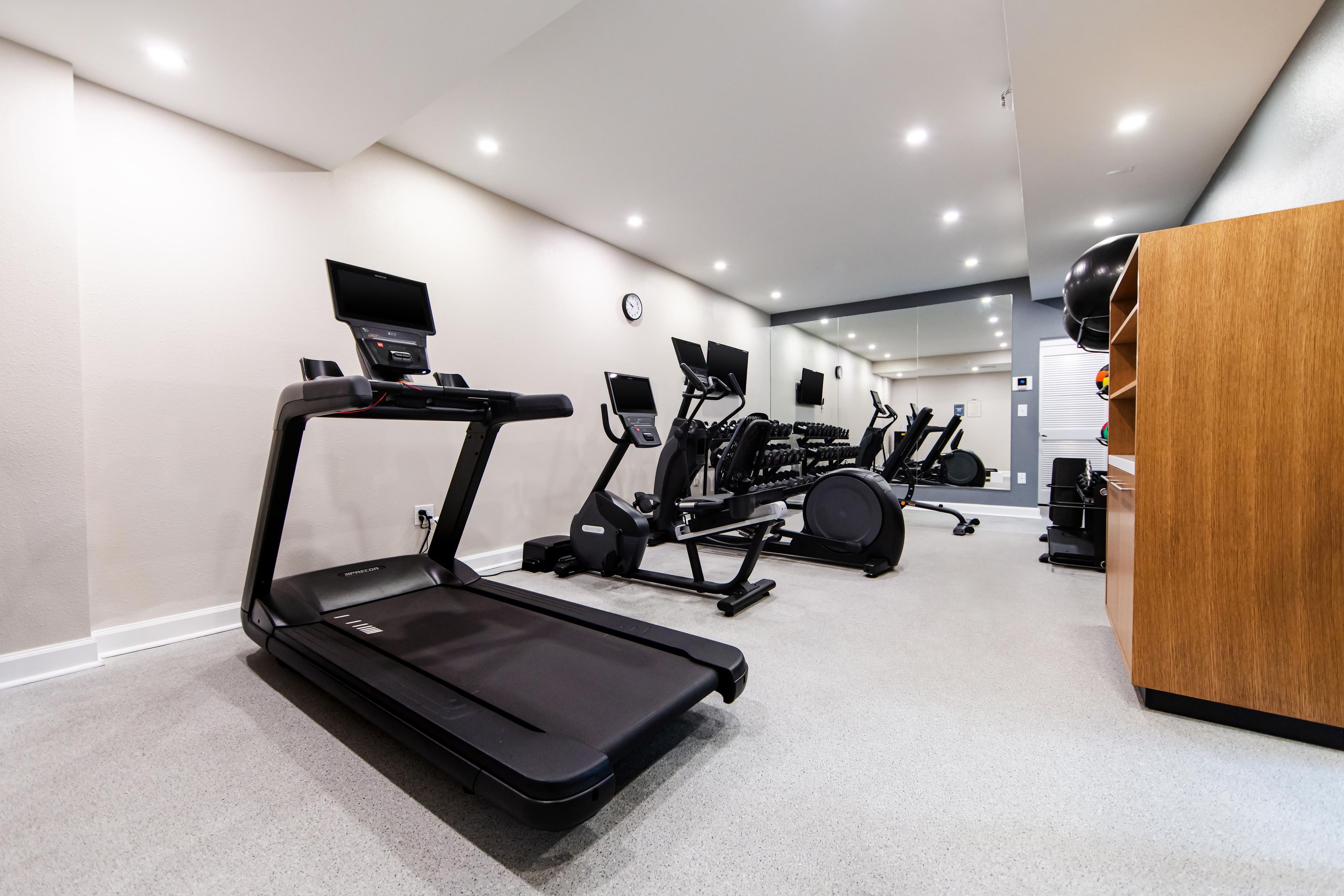 A modern home gym with a treadmill, elliptical, and weight machines.