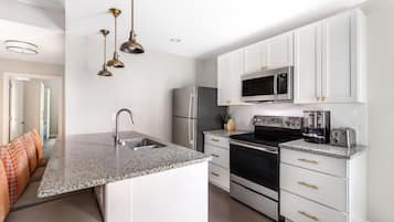 A modern kitchen with white cabinets, stainless steel appliances, and a granite countertop.