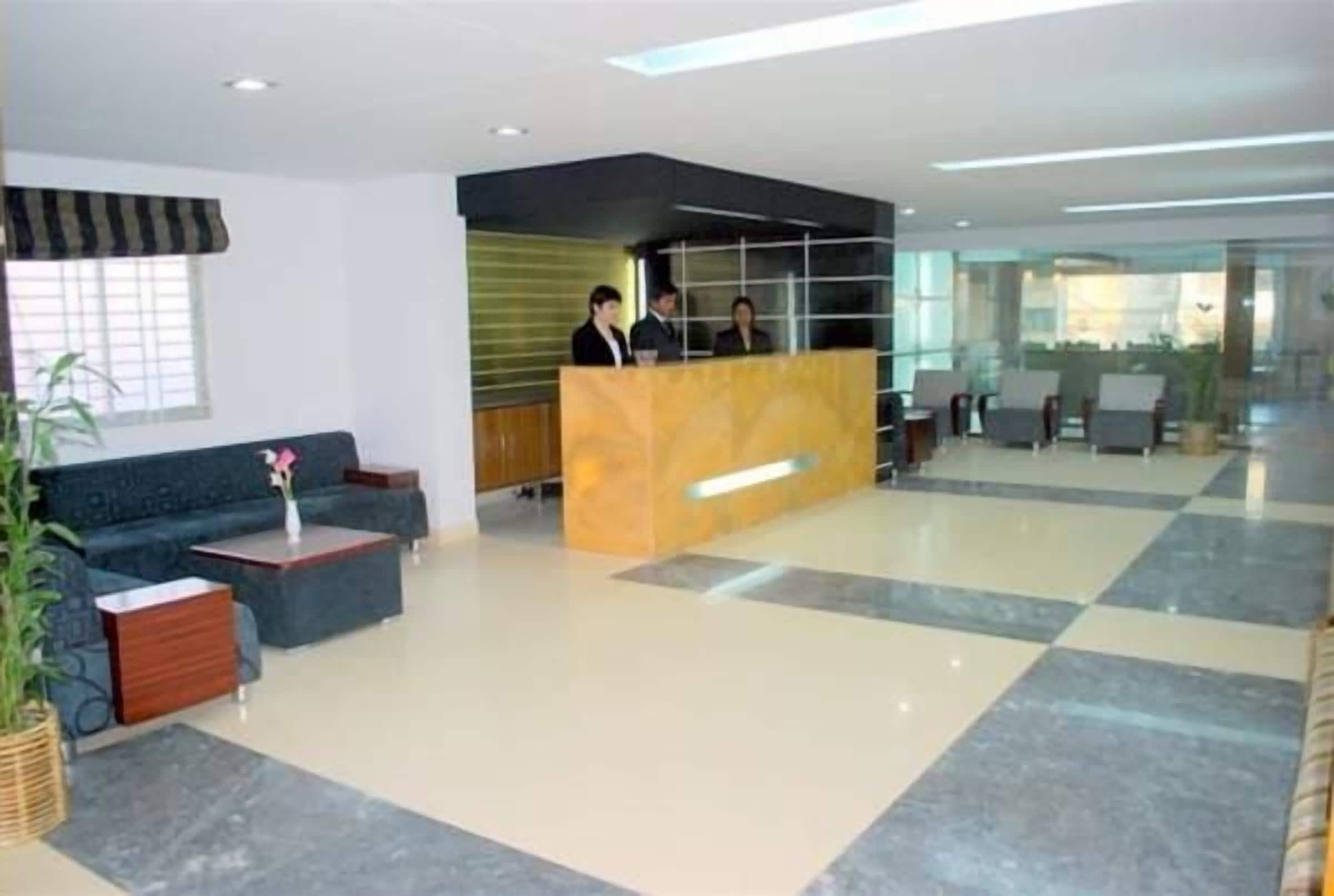 Un vestíbulo de hotel con mostrador de recepción, zona de estar y un amplio ventanal.