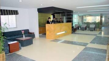 Un vestíbulo de hotel con mostrador de recepción, zona de estar y un amplio ventanal.