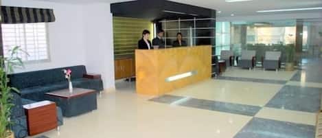 Un vestíbulo de hotel con mostrador de recepción, zona de estar y un amplio ventanal.