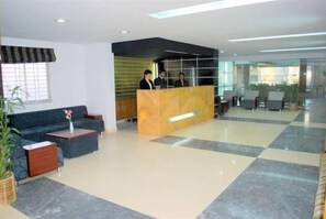 Un vestíbulo de hotel con mostrador de recepción, zona de estar y un amplio ventanal.
