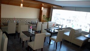 A restaurant with booth seating and tables, featuring a patterned wall and wooden ceiling.