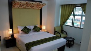 Una habitación de hotel con una cama grande, dos mesitas de noche, una silla y una pequeña mesa.