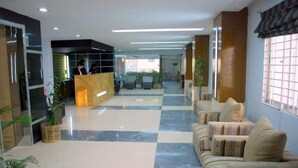 A hotel lobby with a reception desk, seating area, and a checkered floor pattern.