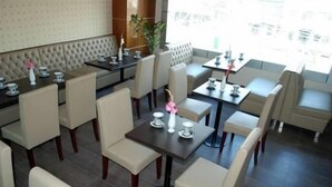 Un restaurante con cabinas y mesas, algunas con manteles blancos, y vistas a la ciudad.