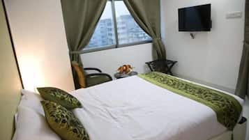 A hotel room with a bed, a television mounted on the wall, and a window with curtains.