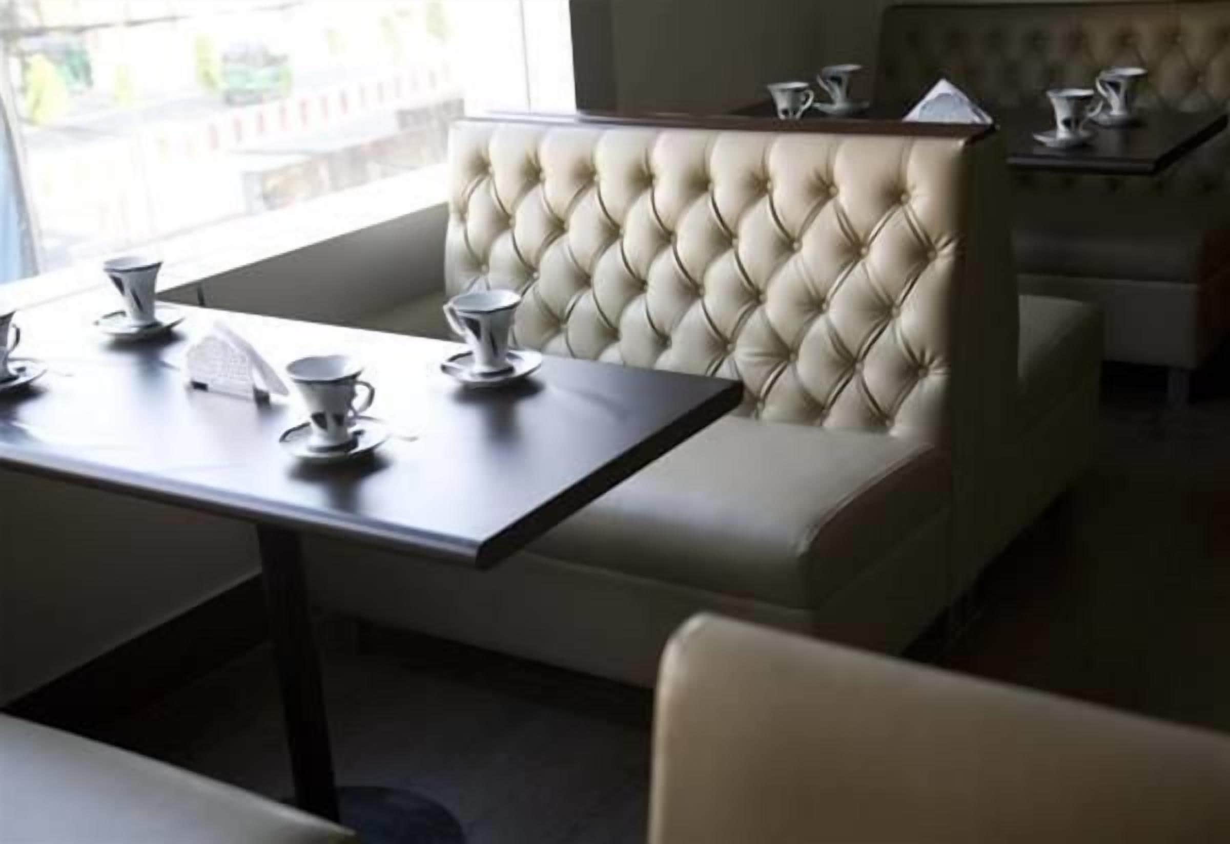 A dining area with a tufted booth and a table set with cups and saucers.