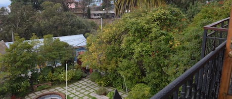 Un jardín con una fuente de ladrillo circular, un banco de madera y una zona pavimentada con diseño de cuadrícula.
