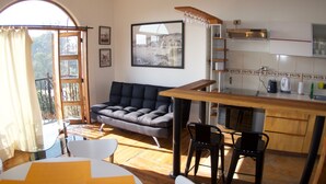 A cozy living room with a sofa, a dining table with chairs, and a kitchen area with a counter and stools. - Lofts Parque Mirador Cerro Alegre (Valparaiso)