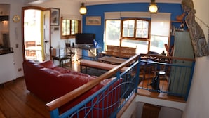 A cozy living room with a red sofa, wooden furniture, and a blue railing. - Lofts Parque Mirador Cerro Alegre (Valparaiso)