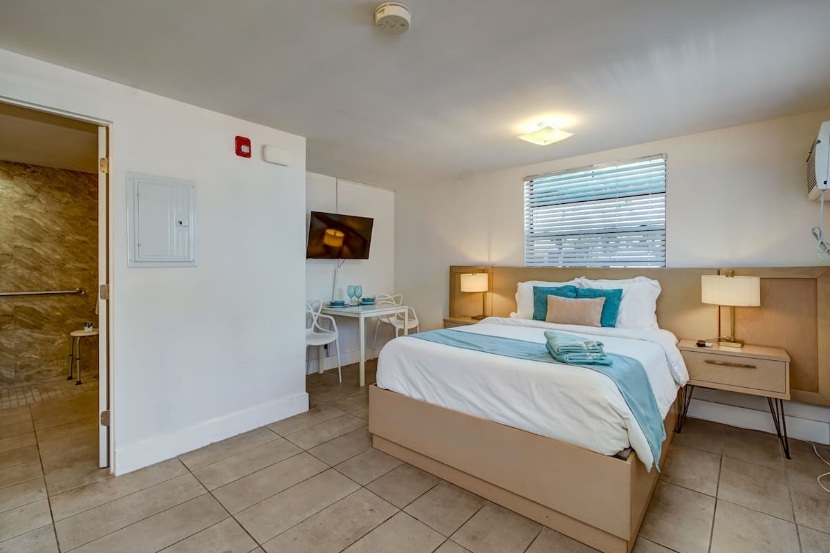 A bedroom with a bed, bedside tables, a desk, and a television.