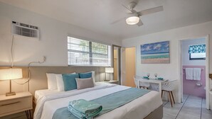 Une chambre bien rangée, avec un lit, une table de chevet, une lampe et un bureau avec des chaises.