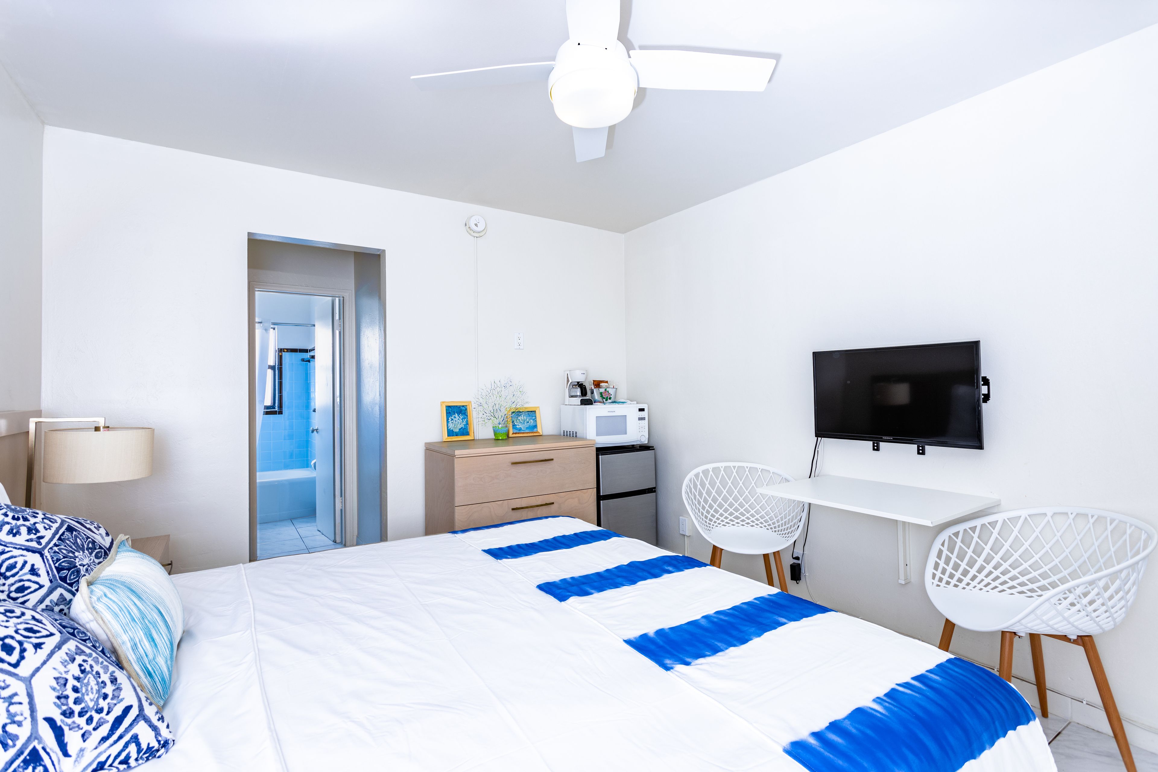 Una habitación de hotel moderna con una cama, un escritorio, un televisor y una silla.
