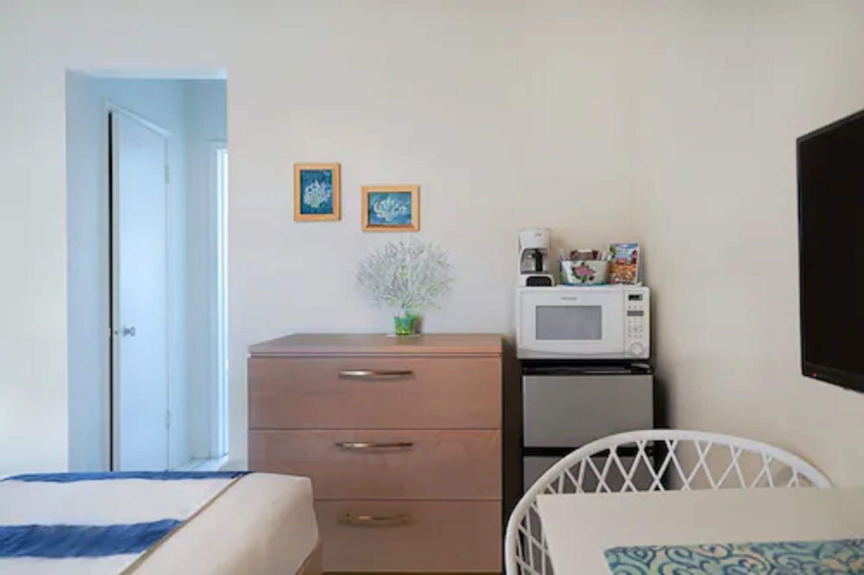 Une chambre avec un lit, une commode, un four à micro-ondes et un réfrigérateur.