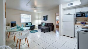 Un espace de vie compact comprenant un coin repas, un canapé, une kitchenette et un ventilateur de plafond.