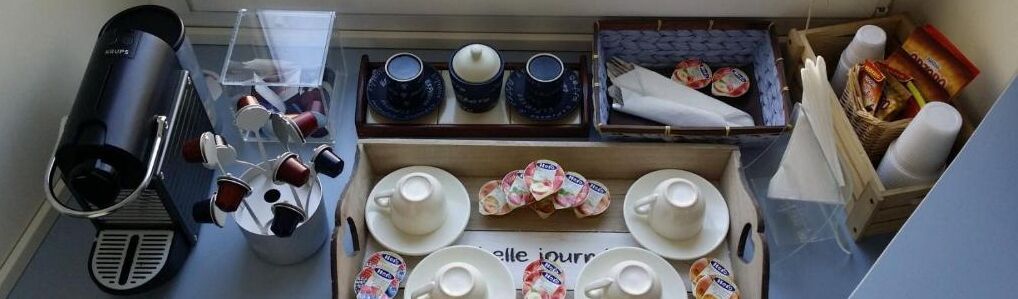 A kitchenette with a coffee machine, tea set, and various kitchen utensils.