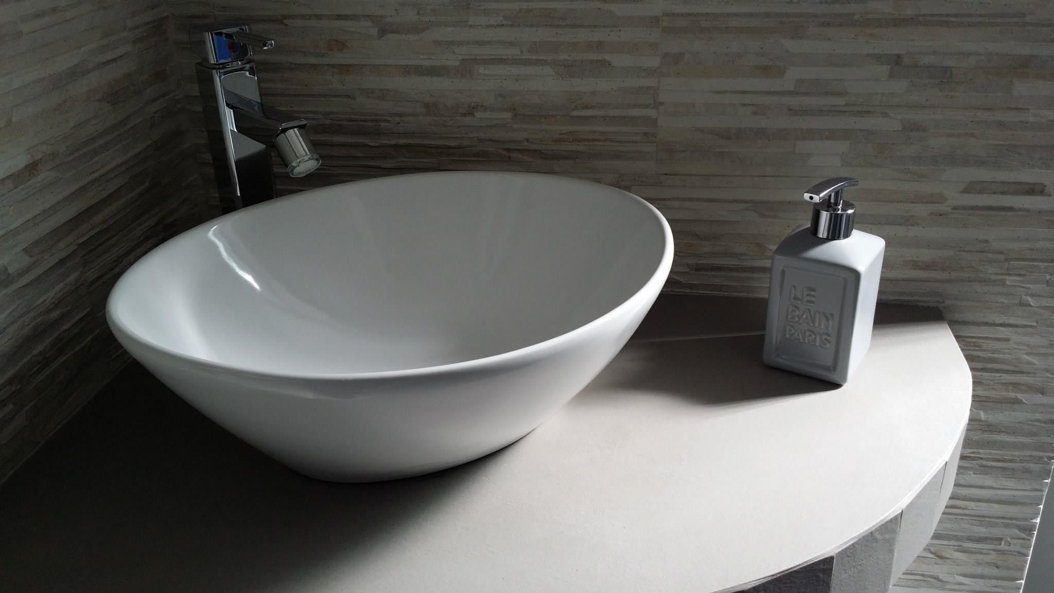 Ein modernes Badezimmer mit einem großen, weißen Waschtischbecken und einer Flasche Cologne von Le Bain Paris.