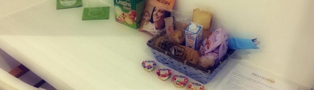 Uma bancada de cozinha com diversos alimentos e embalagens, incluindo uma cesta de pão e petiscos embalados.