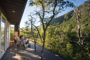A wooden deck with a glass wall overlooking a forested hillside. - Endemiko (Curacautin)