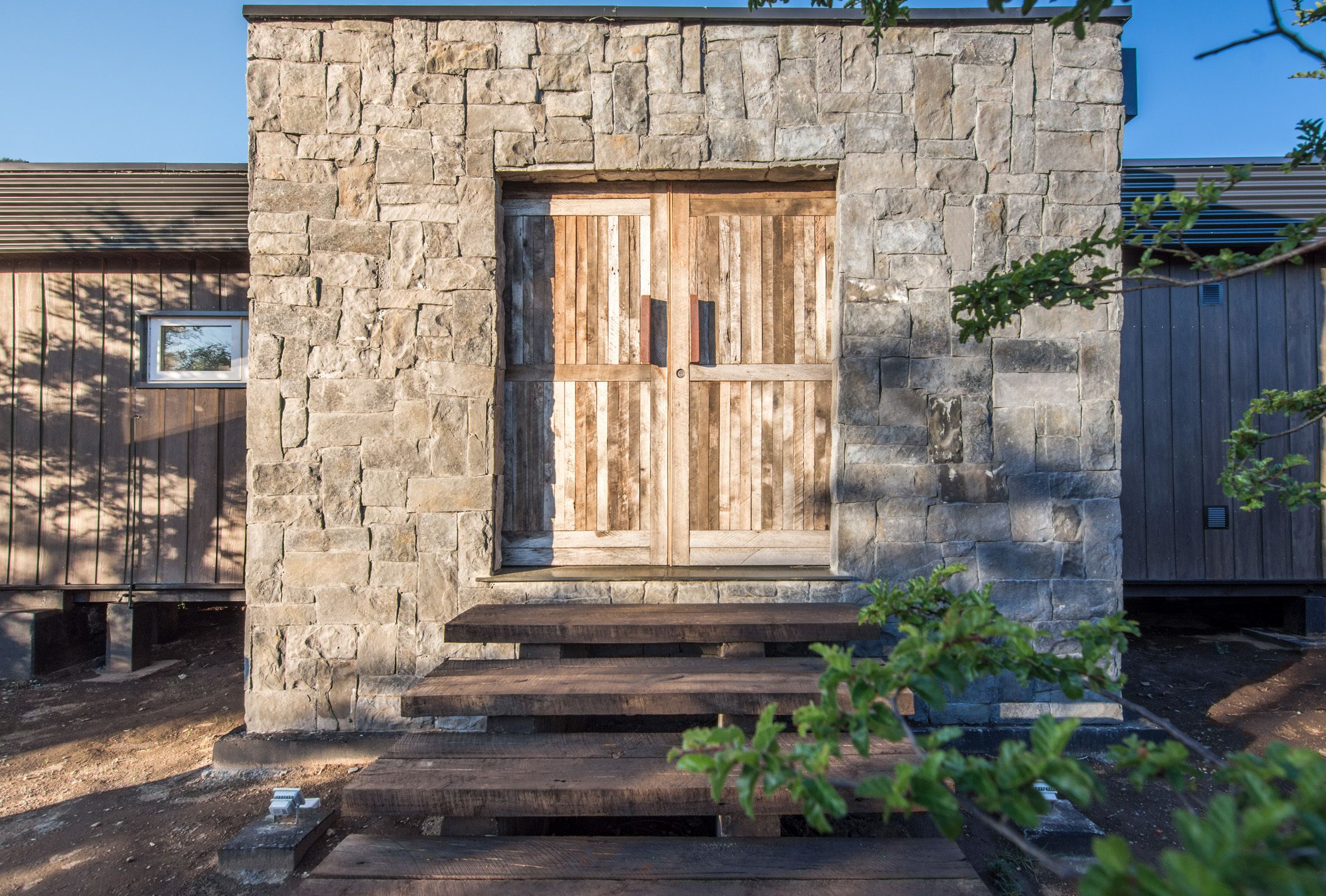 A stone building with a wooden door and steps leading up to it.