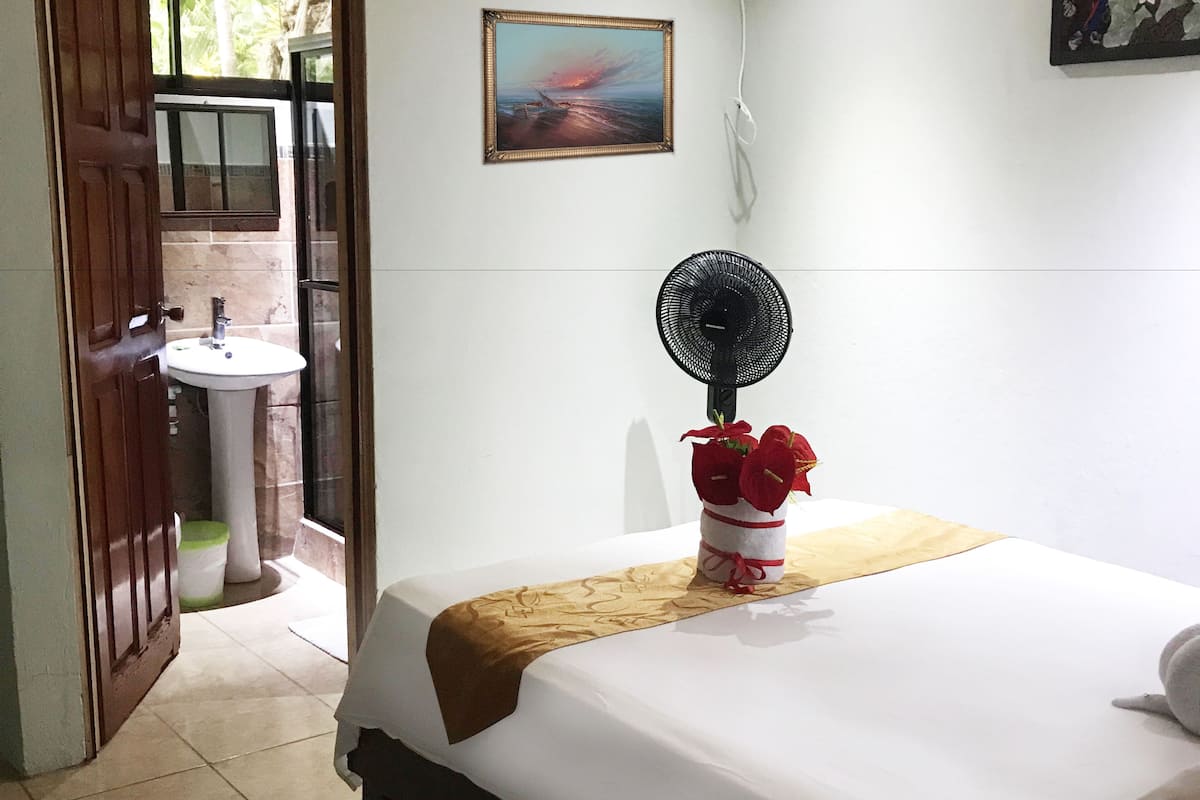 A hotel room with a bed, a bedside table, a sink, and a window.