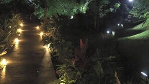 A nighttime garden pathway with illuminated lights and lush greenery. - Manuel Antonio Hostel Resort (Quepos)