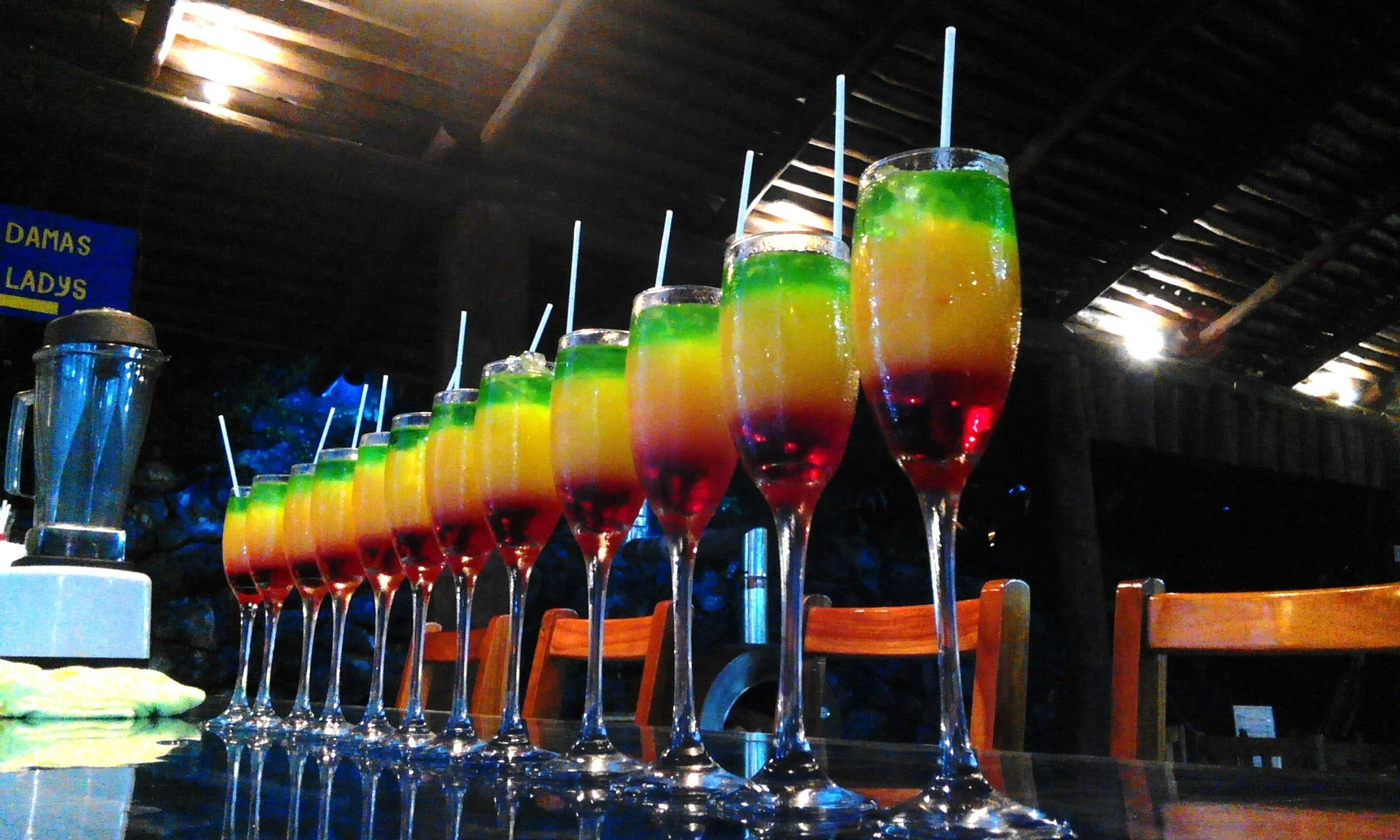 Een rij kleurrijke drankjes op een bar.