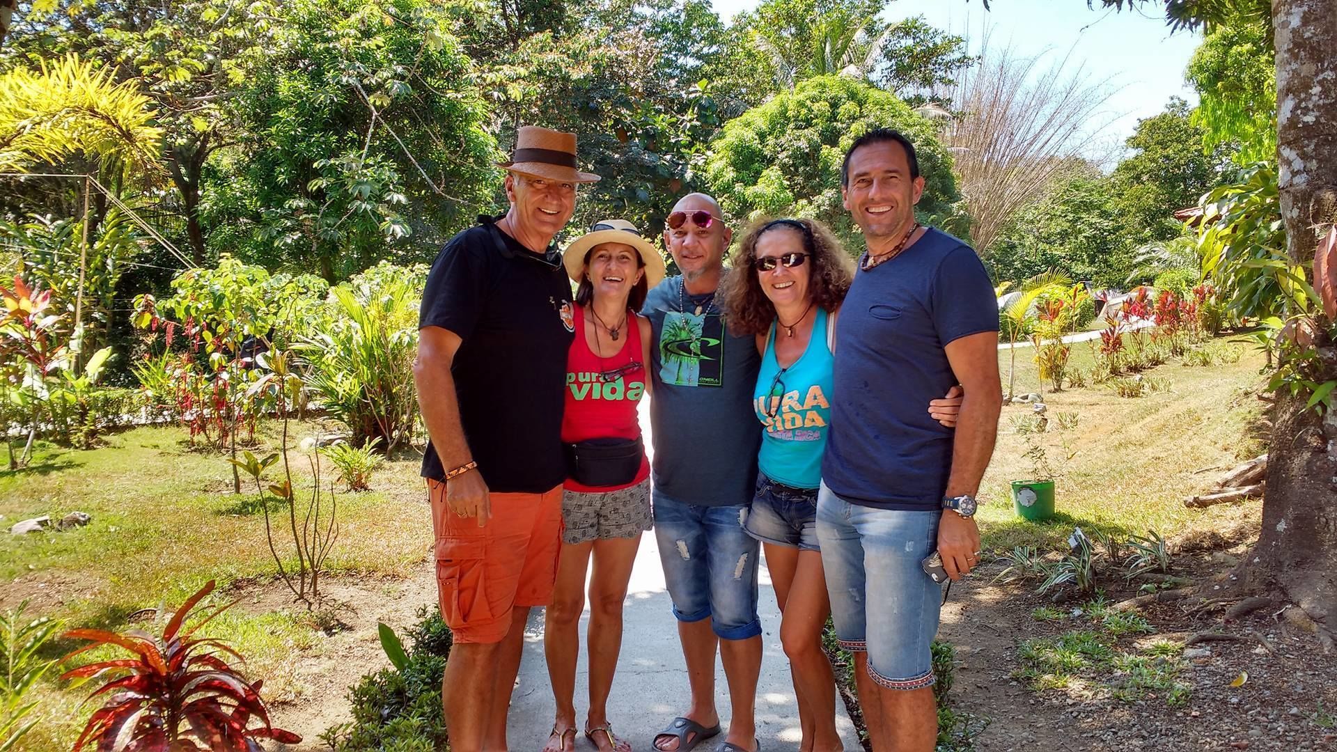 A group of people standing in a garden with various plants and trees.