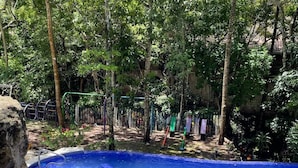 A pool surrounded by trees and a stone wall. - Mayan Hills Resort (Copan Ruinas)
