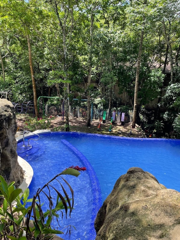 Ein Pool, umgeben von Bäumen und einer Steinmauer.