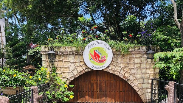 A stone archway with a wooden door, a sign above reading "Jungling Hotel & Spa," and a stone pathway leading through. - Mayan Hills Resort (Copan Ruinas)