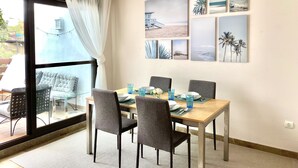 A dining area with a wooden table, four chairs, and a hanging light fixture.