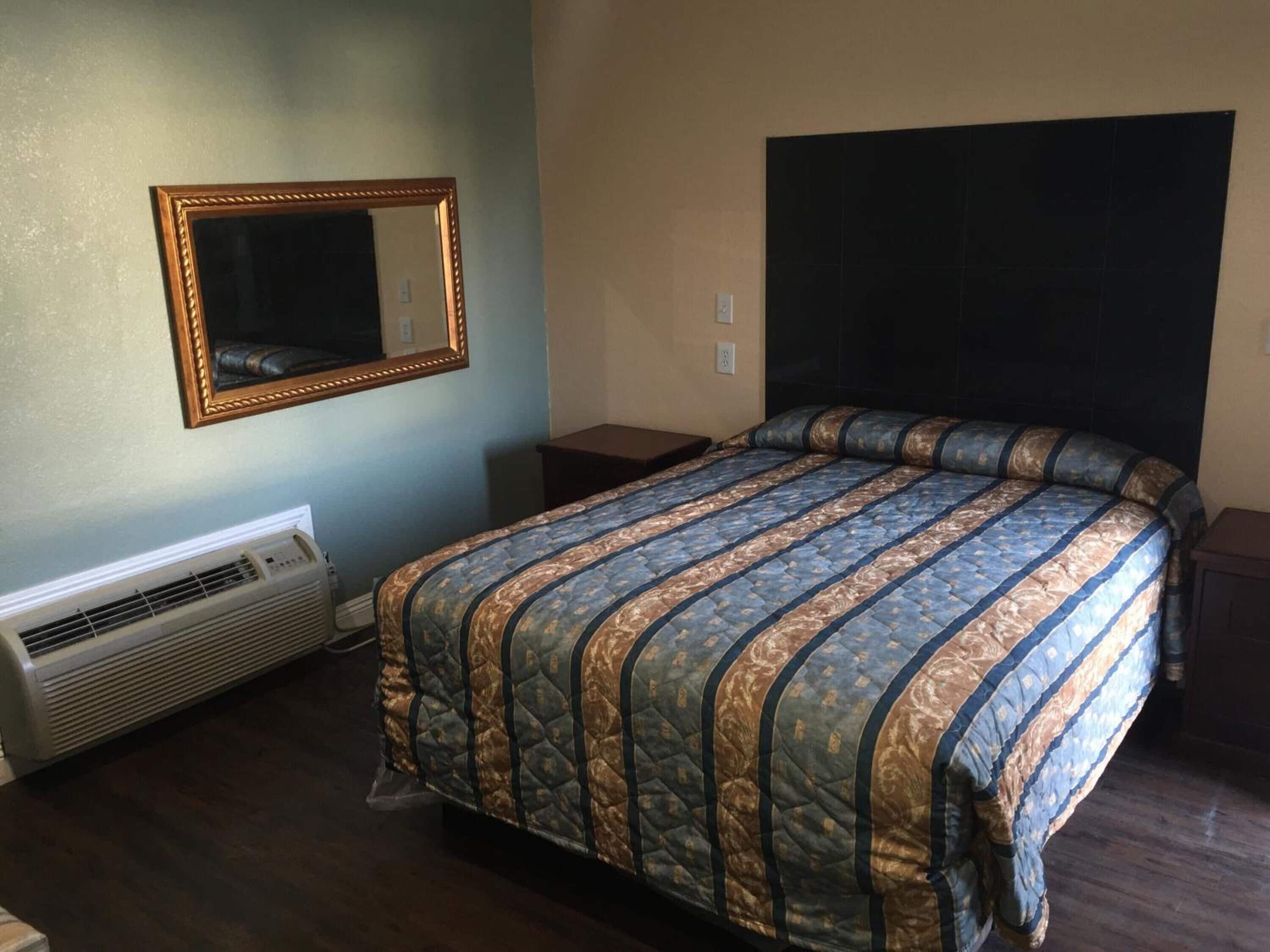 Ein Schlafzimmer mit einem Bett, einem Spiegel, einer Heizung und einem dunklen Kopfteil.