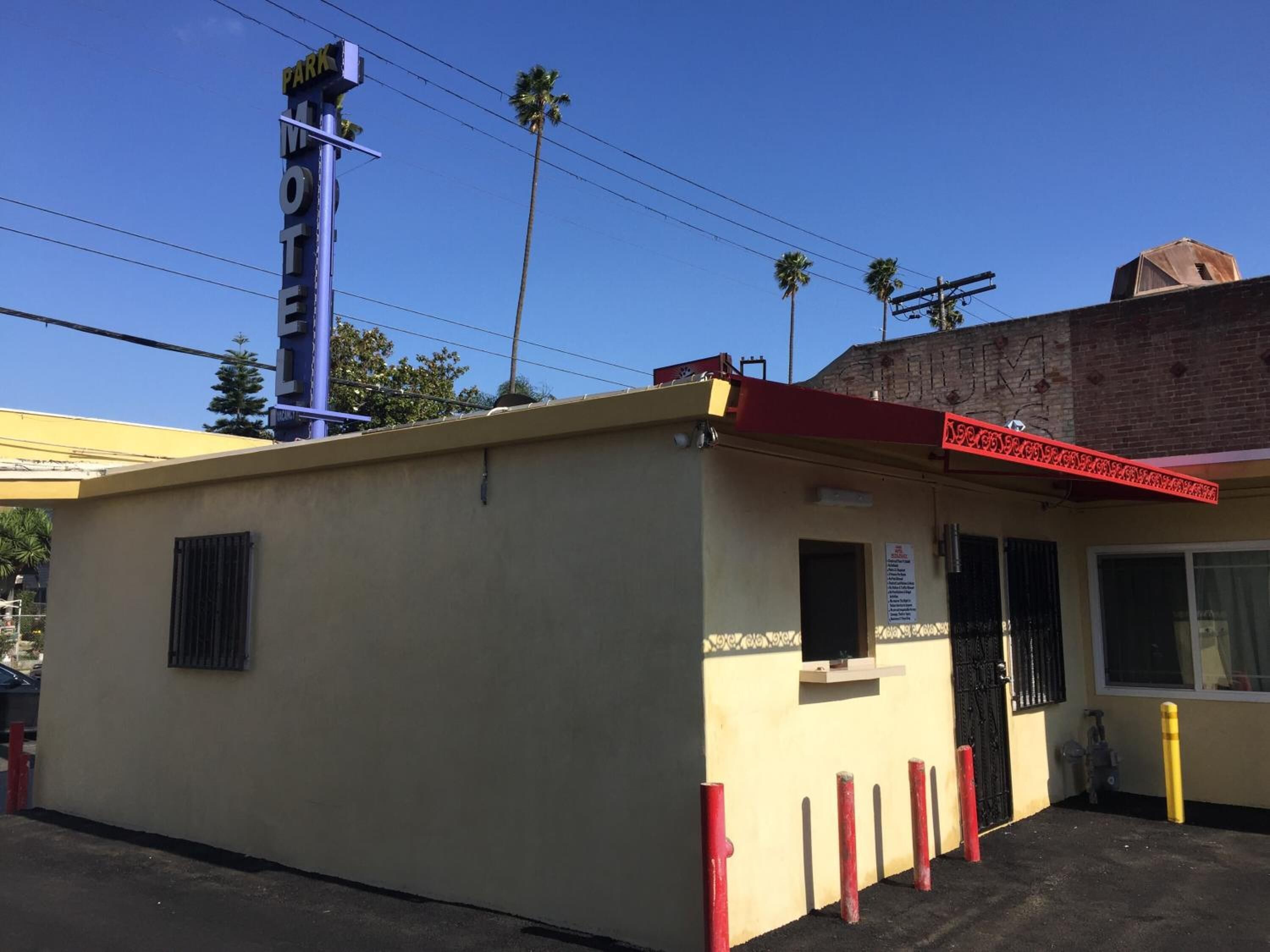 A small, single-story motel with a beige exterior and a red awning. There is a sign on the building that reads "Motel."