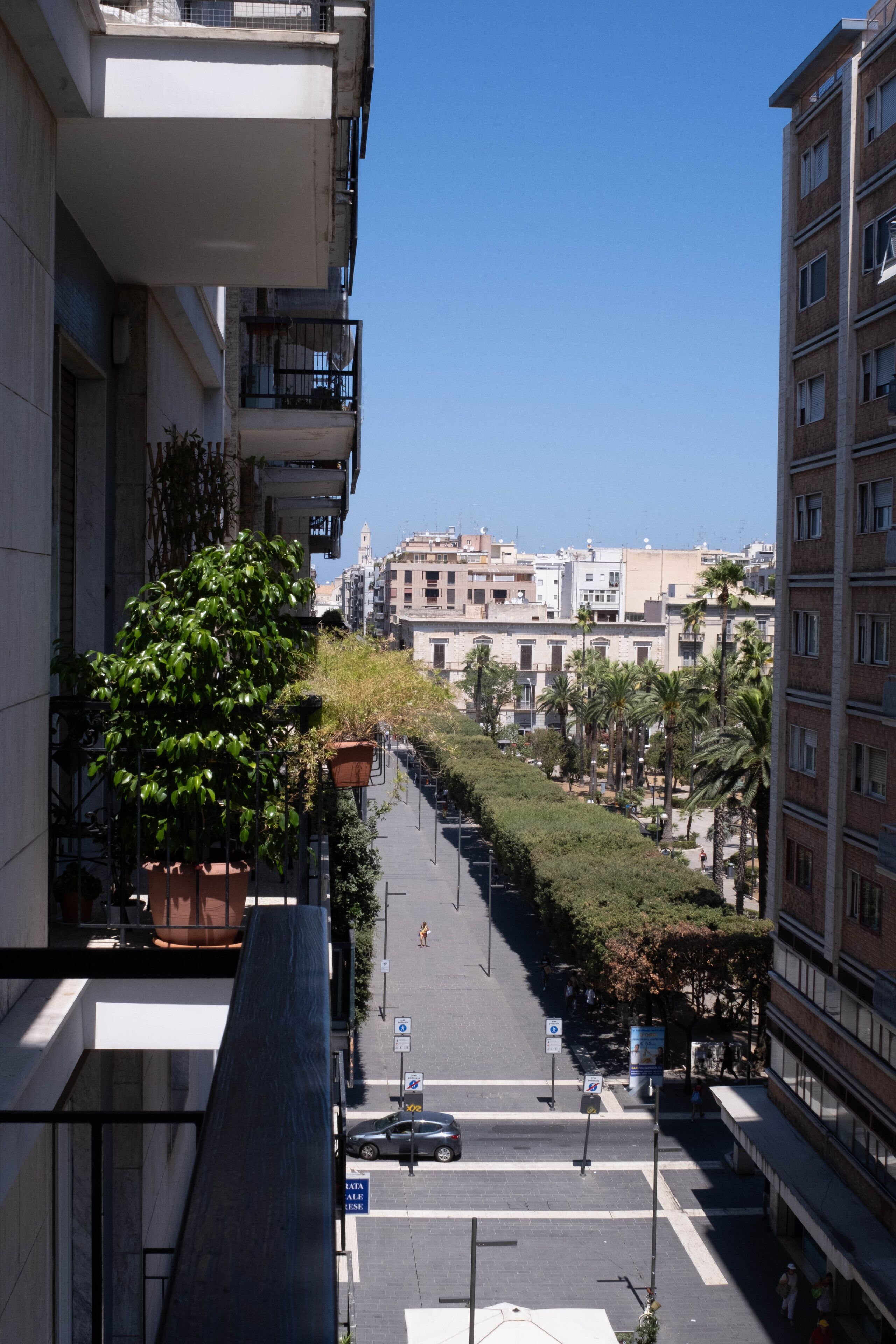 Straßenansicht mit Gebäuden, einer Fußgängerampel und blauem Himmel.