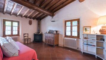 Une chambre avec un plafond en bois, un lit avec une literie rose, une commode et un radiateur.