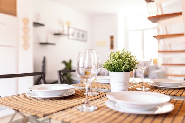 Una mesa de comedor preparada con platos, vasos y una planta en maceta.