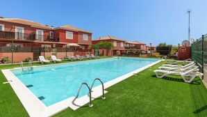 Una piscina con lettini bianchi e prato sintetico.