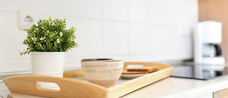 A kitchen counter with a coffee cup, a wooden tray, and a potted plant.