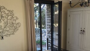 Ein Schlafzimmer mit Bett, einer Kandelaber, einem Kleiderschrank und Blick durch eine Glastür.