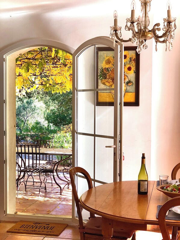 An open door leading to a patio with a table, chairs, and a bottle of wine. - Mansion - Correns (Correns)