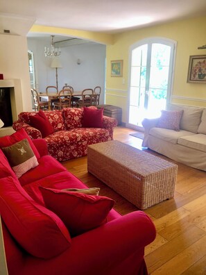 A living room with a red patterned sofa, a white sofa, and a wicker ottoman. - Mansion - Correns (Correns)